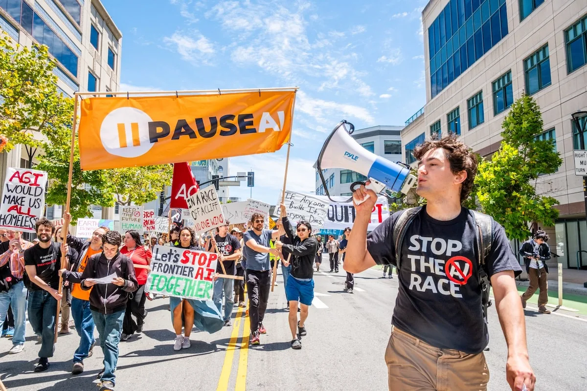 A protester leads chants with a megaphone ahead of a ‘Pause AI’ banner during the march