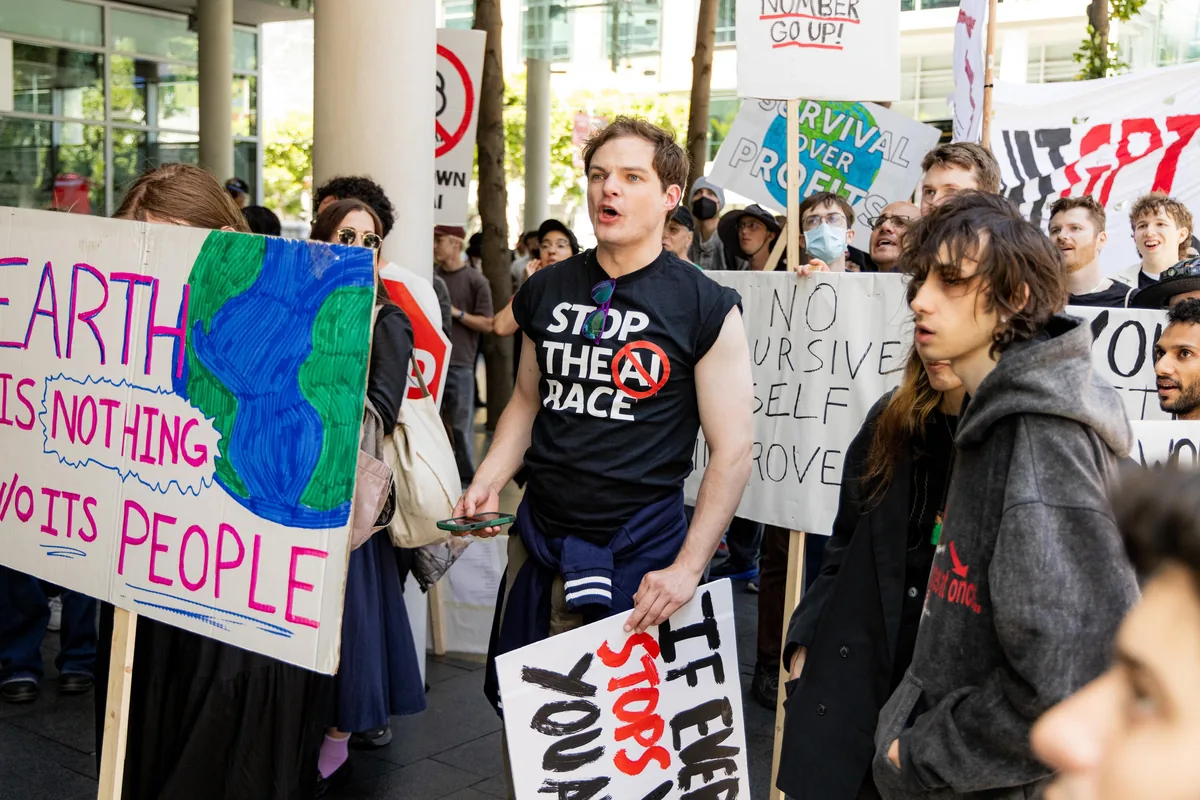 A protester in a ‘Stop the AI Race’ shirt among a crowd holding hand-painted signs